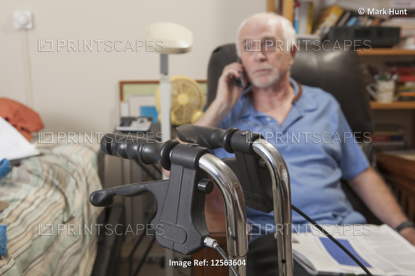 Man with Ataxia with his walker and talking on his cell phone in his bedroom