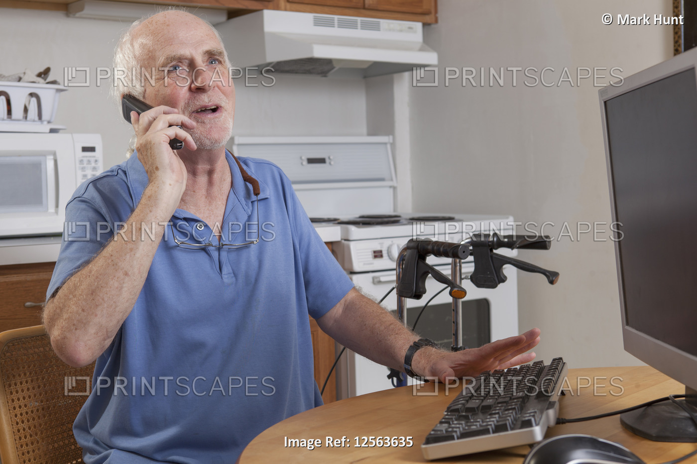 Man with Ataxia talking on his cell phone at the computer in the kitchen