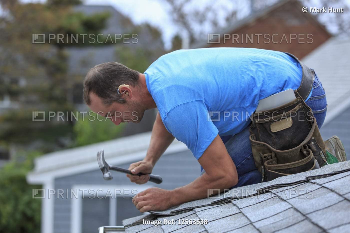 Roofer with hearing aid on his ear working on the new roof