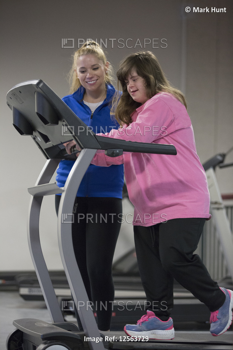 Young woman with Down Syndrome working out with her trainer on an exercise ...