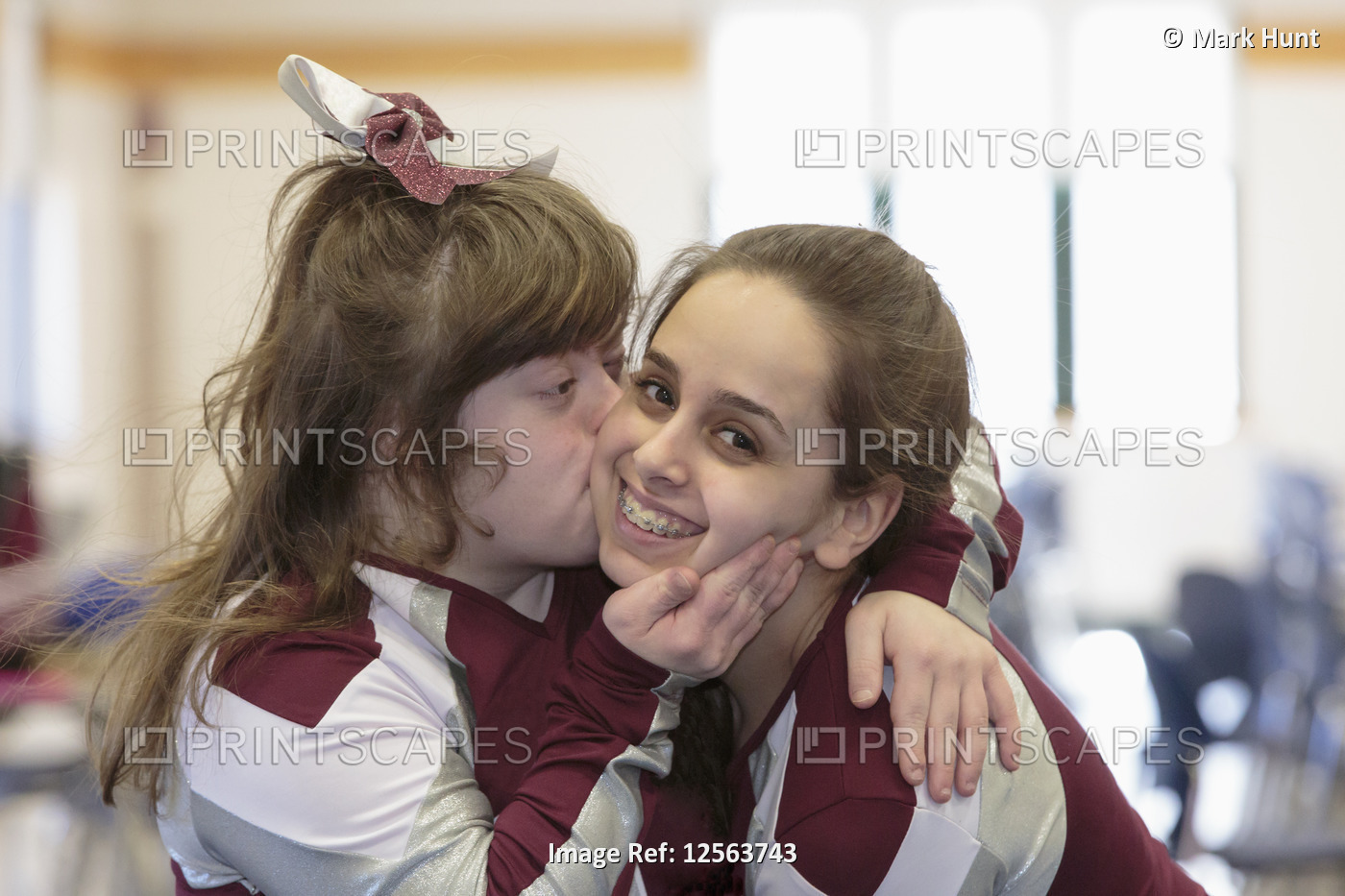 Cheerleader with Down Syndrome kissing another cheerleader