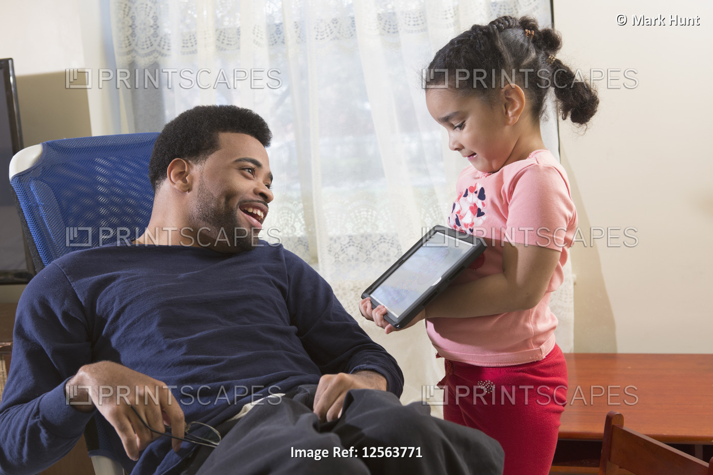 Happy African American man with Cerebral Palsy with his daughter using a tablet ...