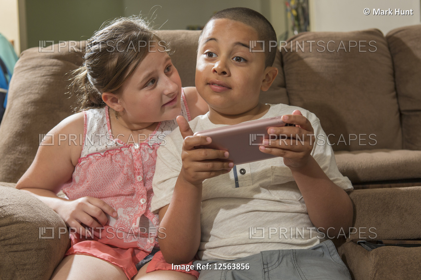 Hispanic boy with Autism playing an electronic game with his sister at home