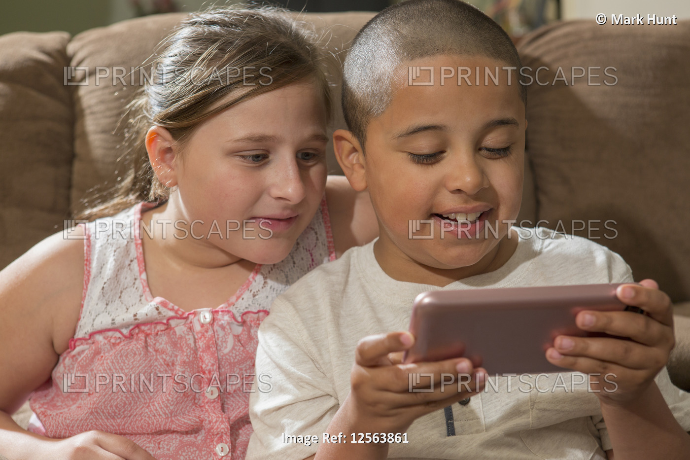 Hispanic boy with Autism playing an electronic game with his sister at home