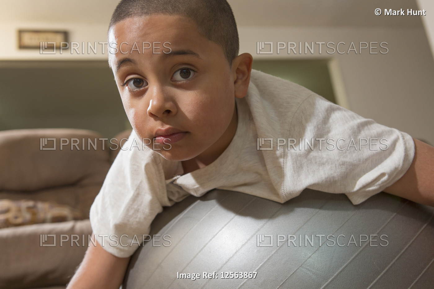 Hispanic boy with Autism playing with an exercise ball in living room