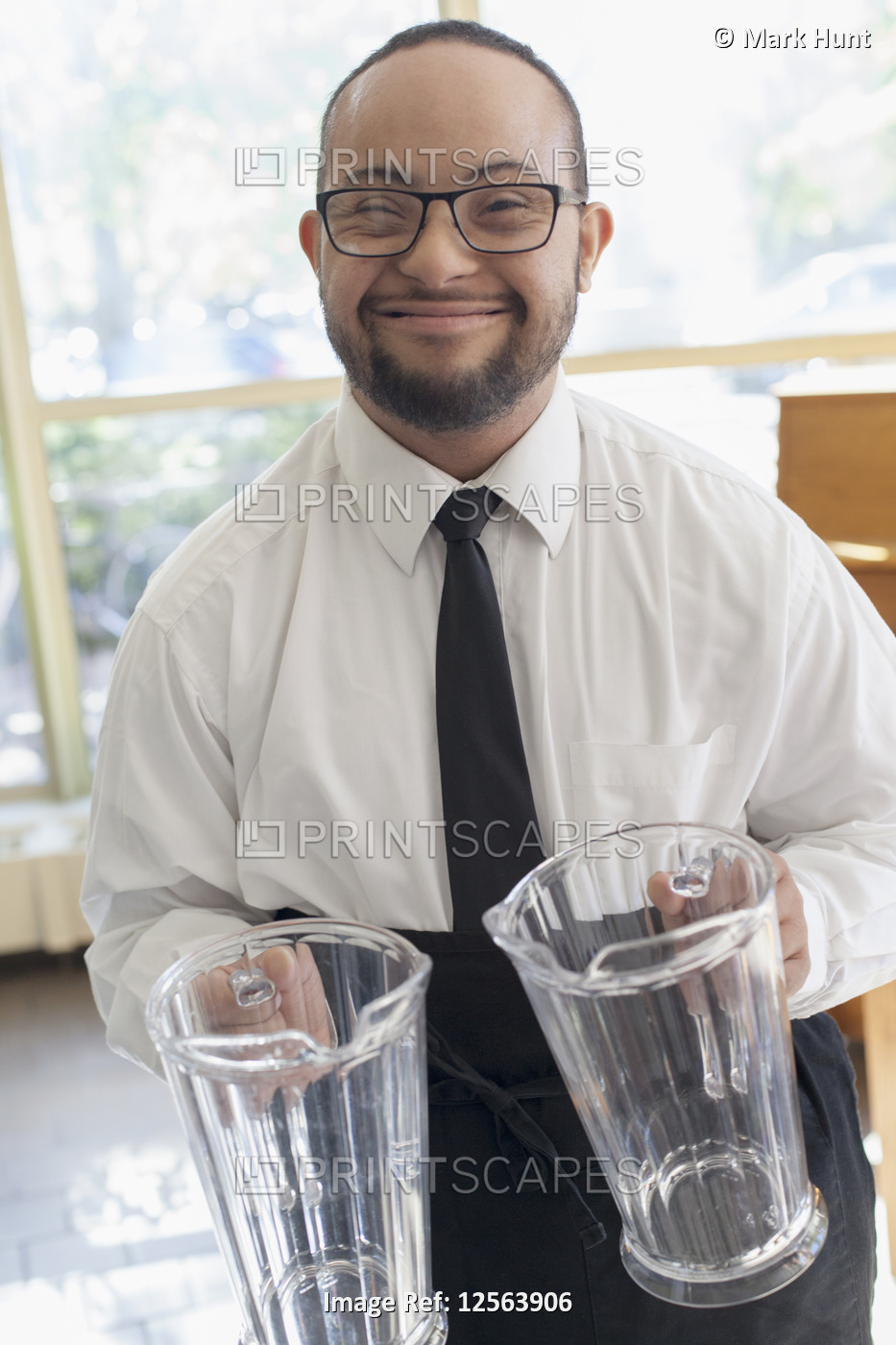 Portrait of African American man with Down Syndrome as a waiter holding glass ...