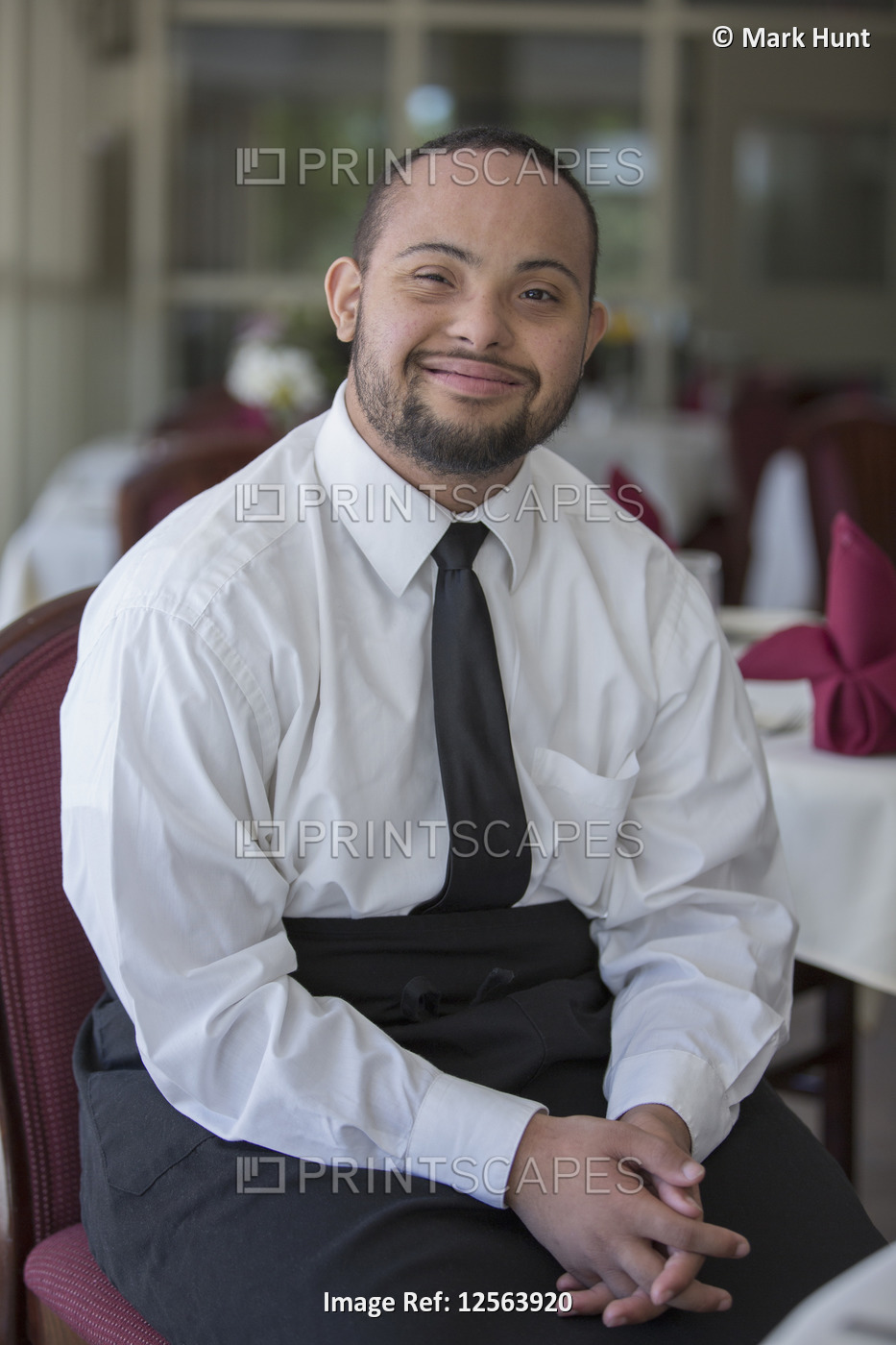 Portrait of happy African American man with Down Syndrome as a waiter in ...
