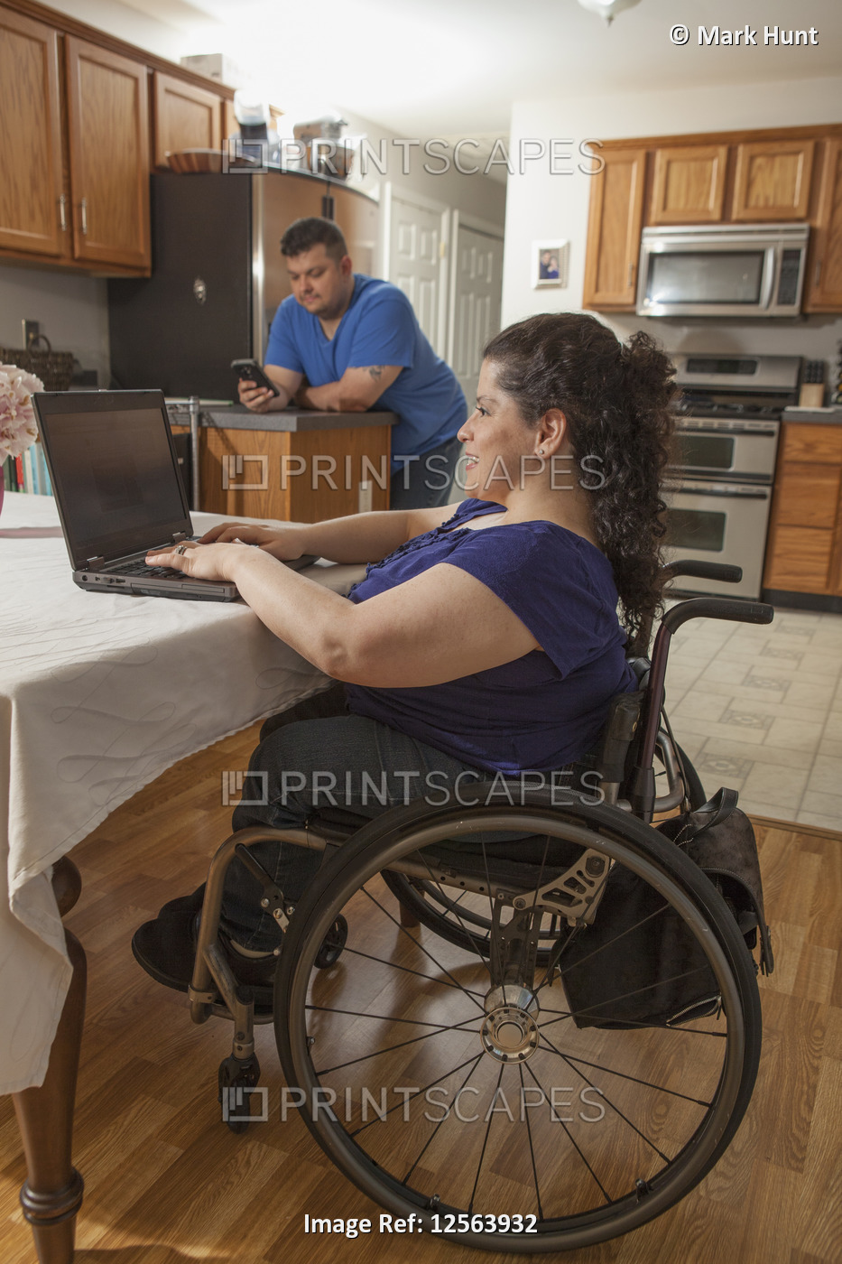Woman with Spina Bifida using computer with her husband using phone at home
