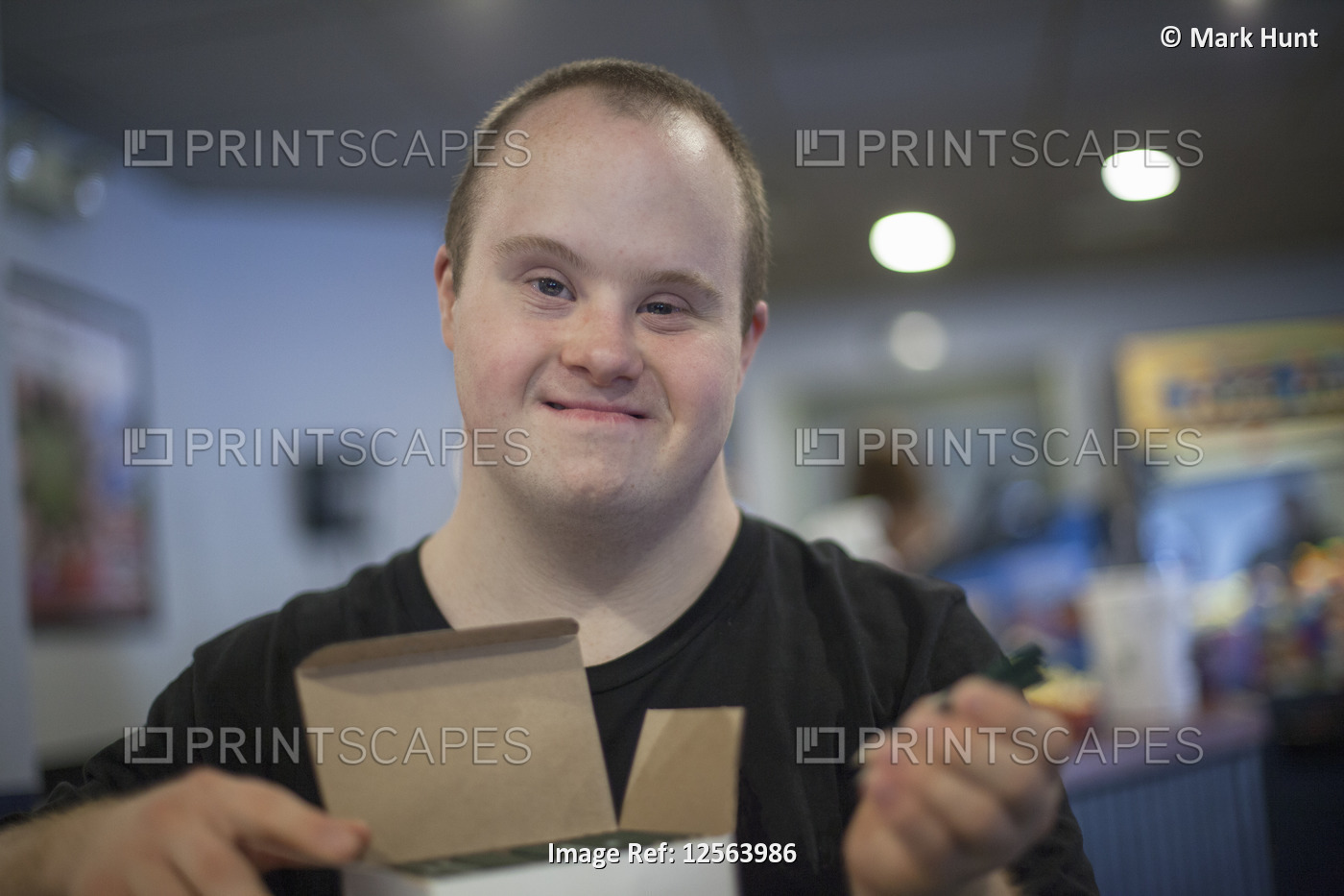 Portrait of happy waiter with Down Syndrome doing preparation in a restaurant
