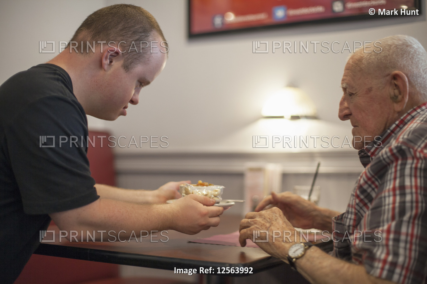 Waiter with Down Syndrome serving food to customer in a restaurant