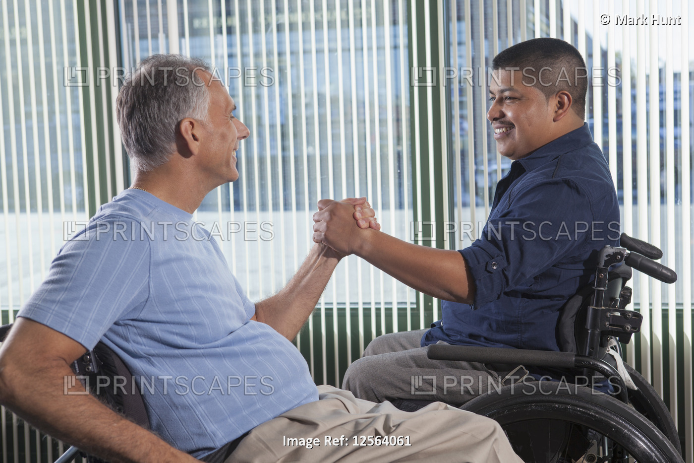 Two men with Spinal Cord Injuries shaking hands in an office