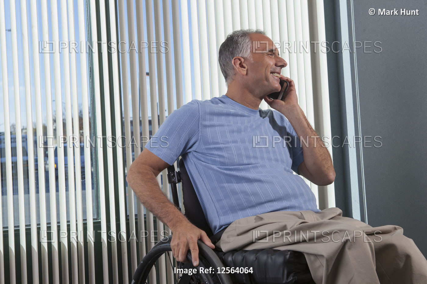 Man with Spinal Cord Injury in wheelchair talking on phone in an office
