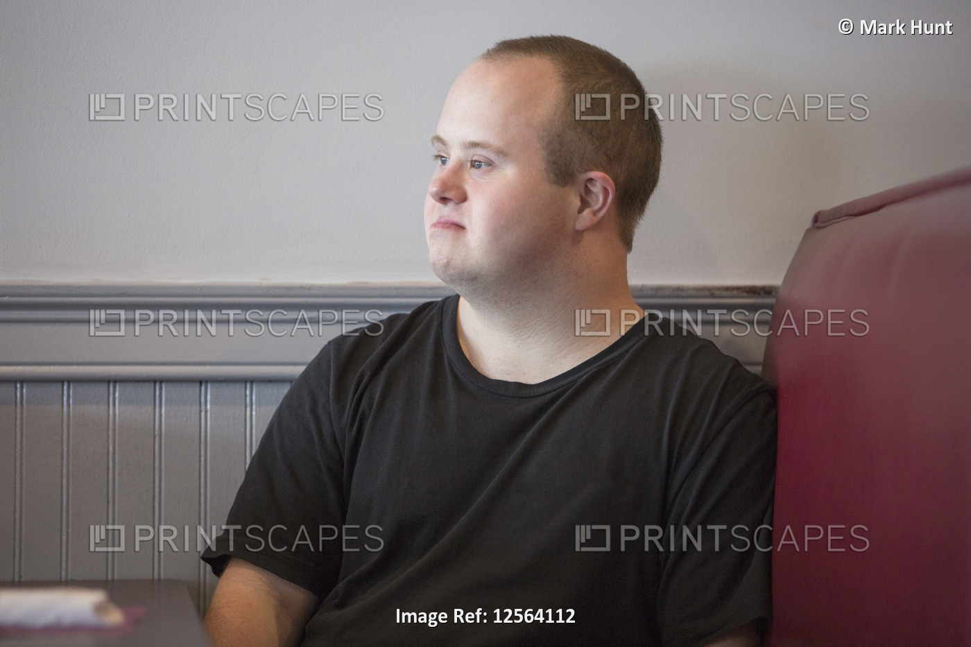 Waiter with Down Syndrome sitting on chair in a restaurant