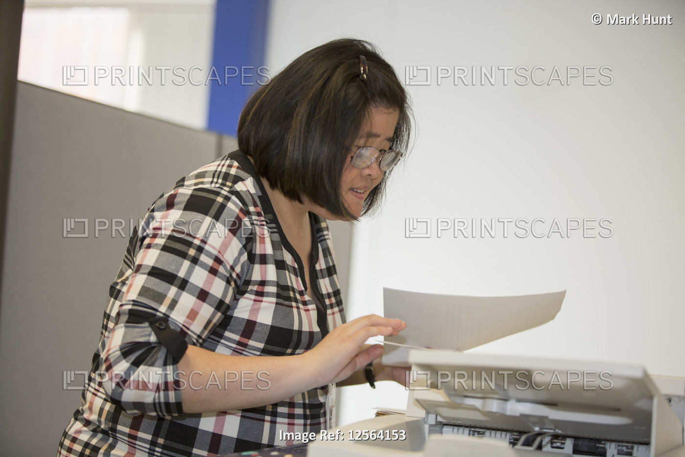 Asian woman with a Learning Disability working at a copy machine in office