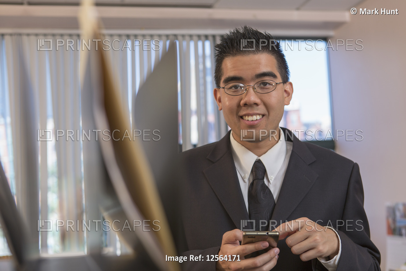 Asian man with Autism working in an office with his phone
