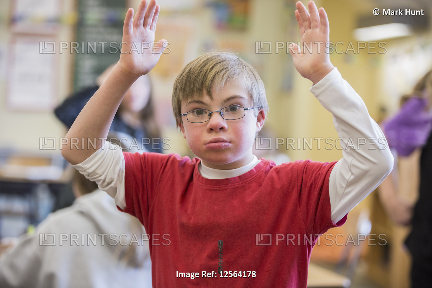 Boy with Down syndrome arms raised in a school classroom
