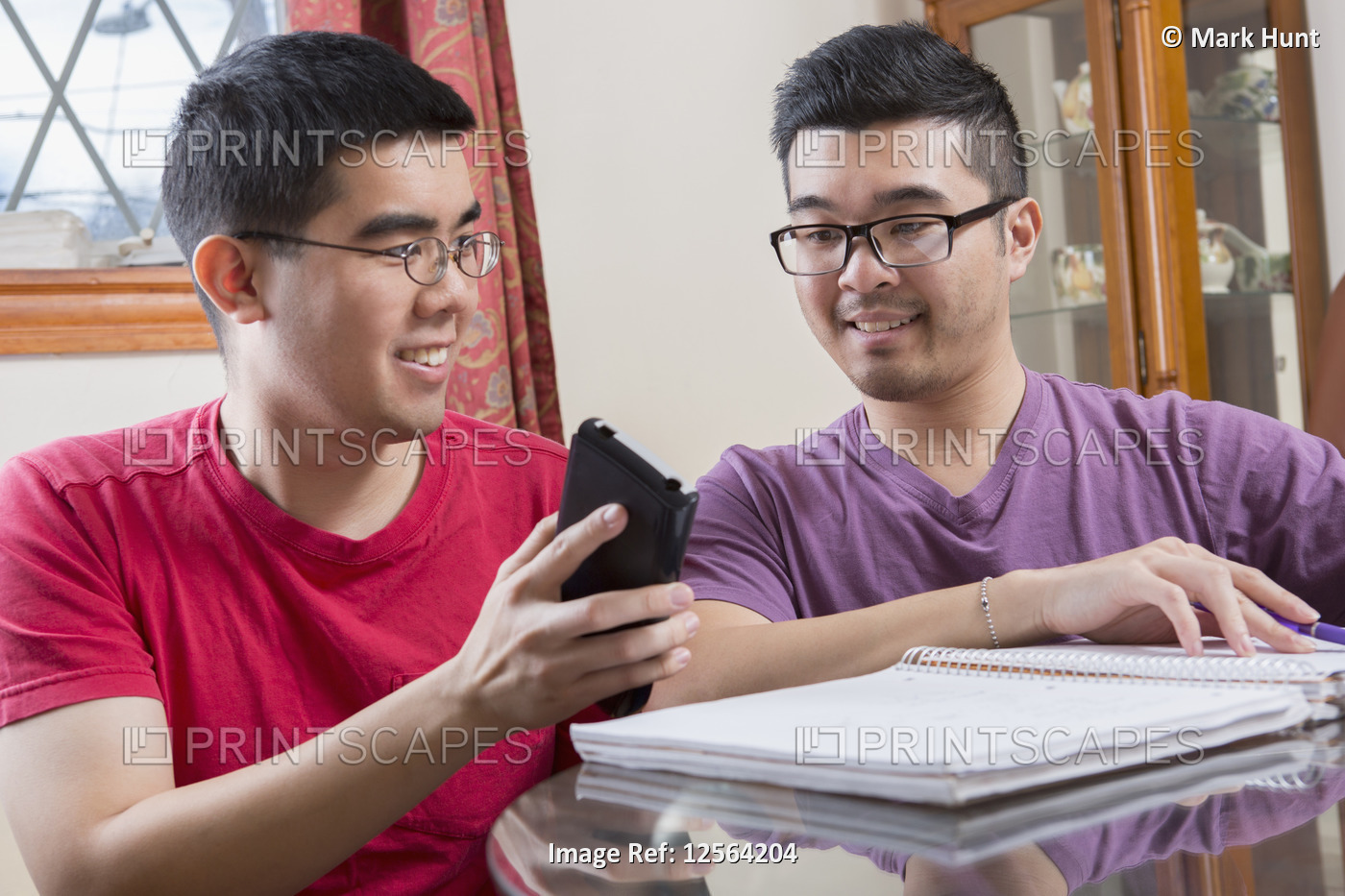 Asian man with Autism showing phone to his brother
