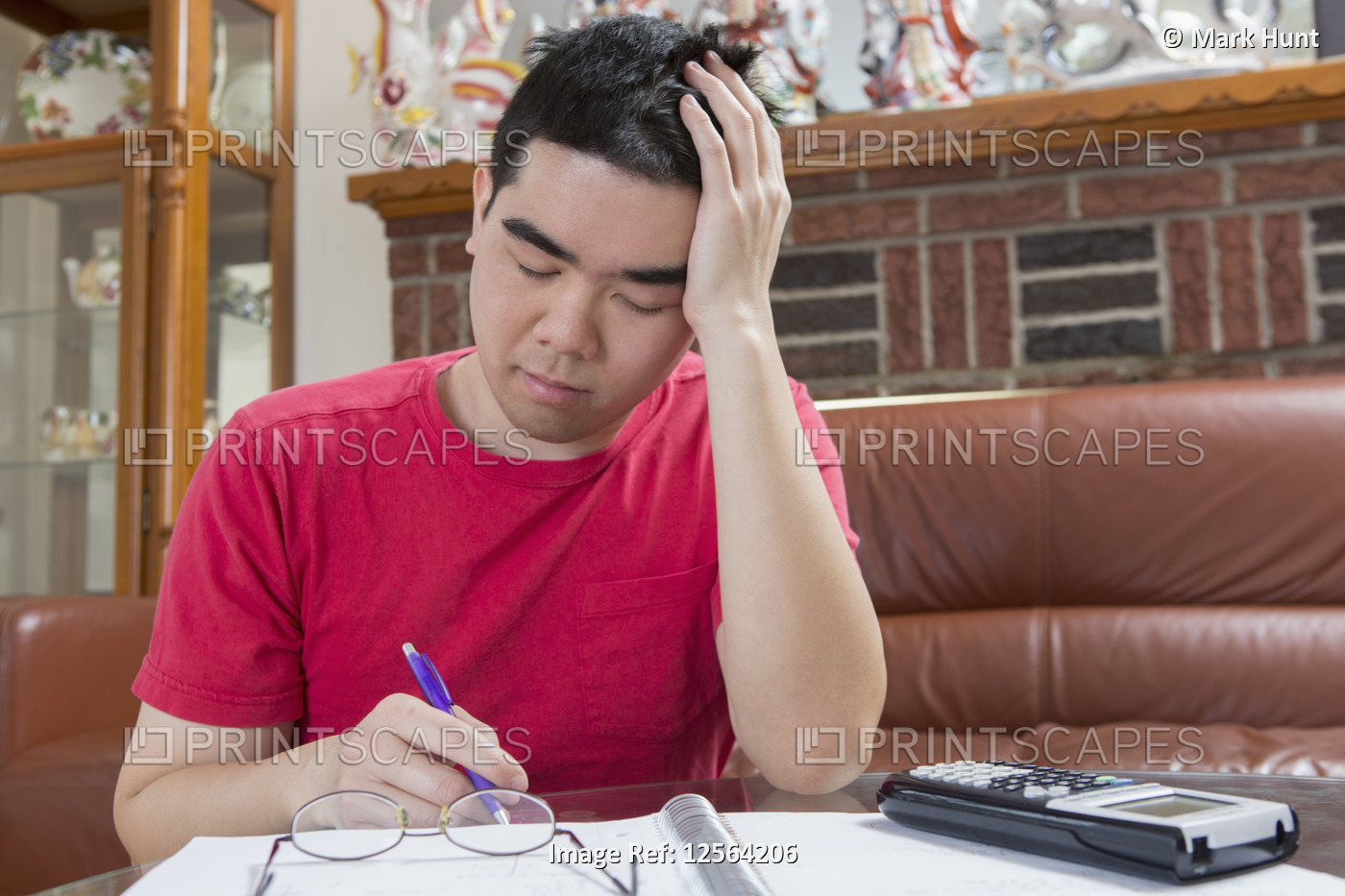 Asian man with Autism working on his homework and getting tired