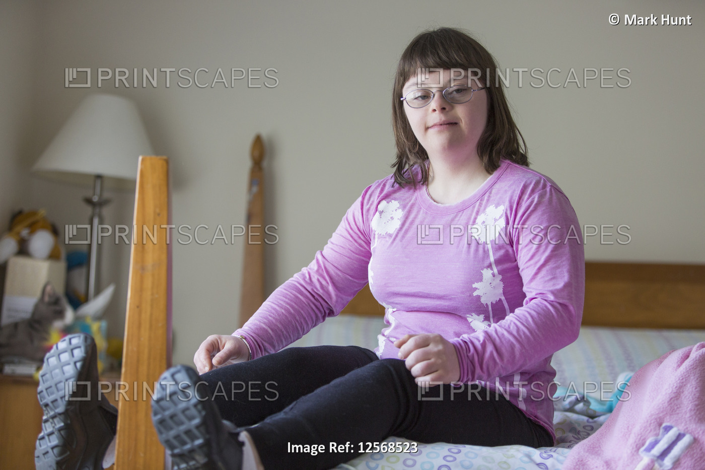 Girl with Down Syndrome sitting on her bed