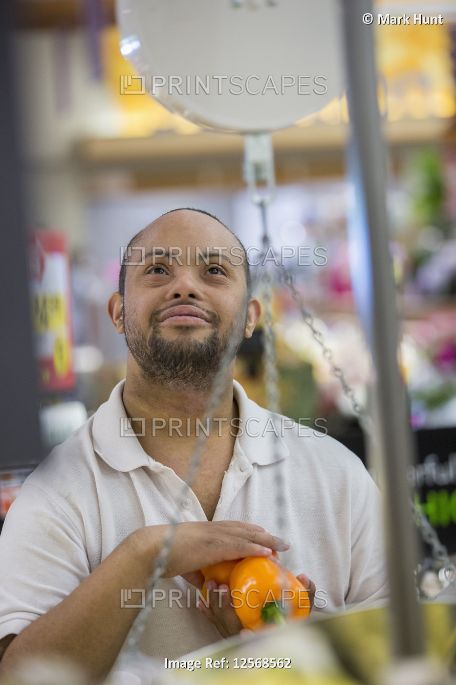 Man with Down Syndrome weighing vegetable in a grocery store