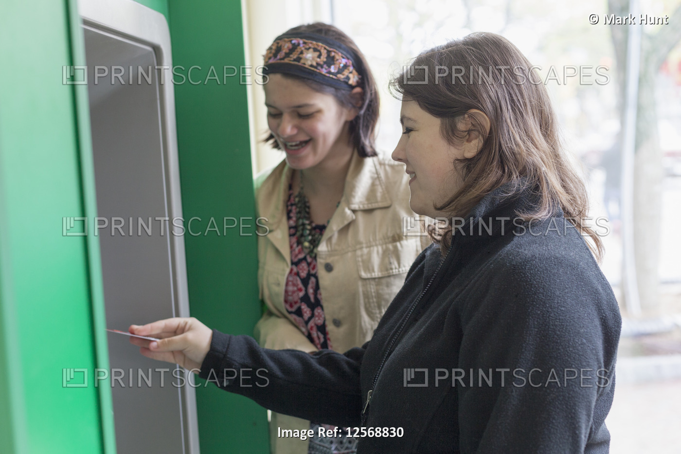 Two female friends using an ATM, one with Traumatic Brain Injury and one Amputee