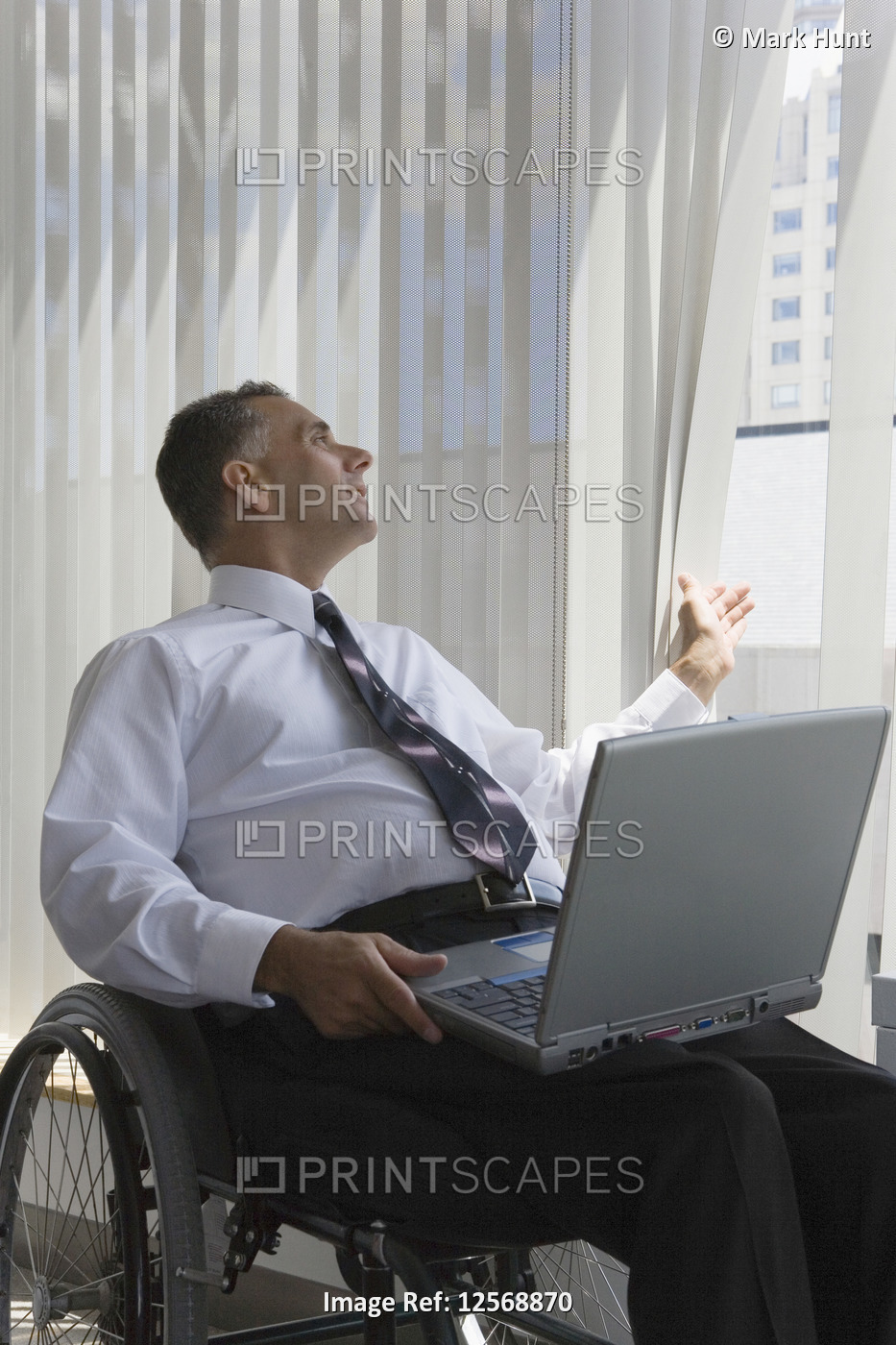 Businessman with a Spinal Cord Injury sitting in a wheelchair with a laptop on ...