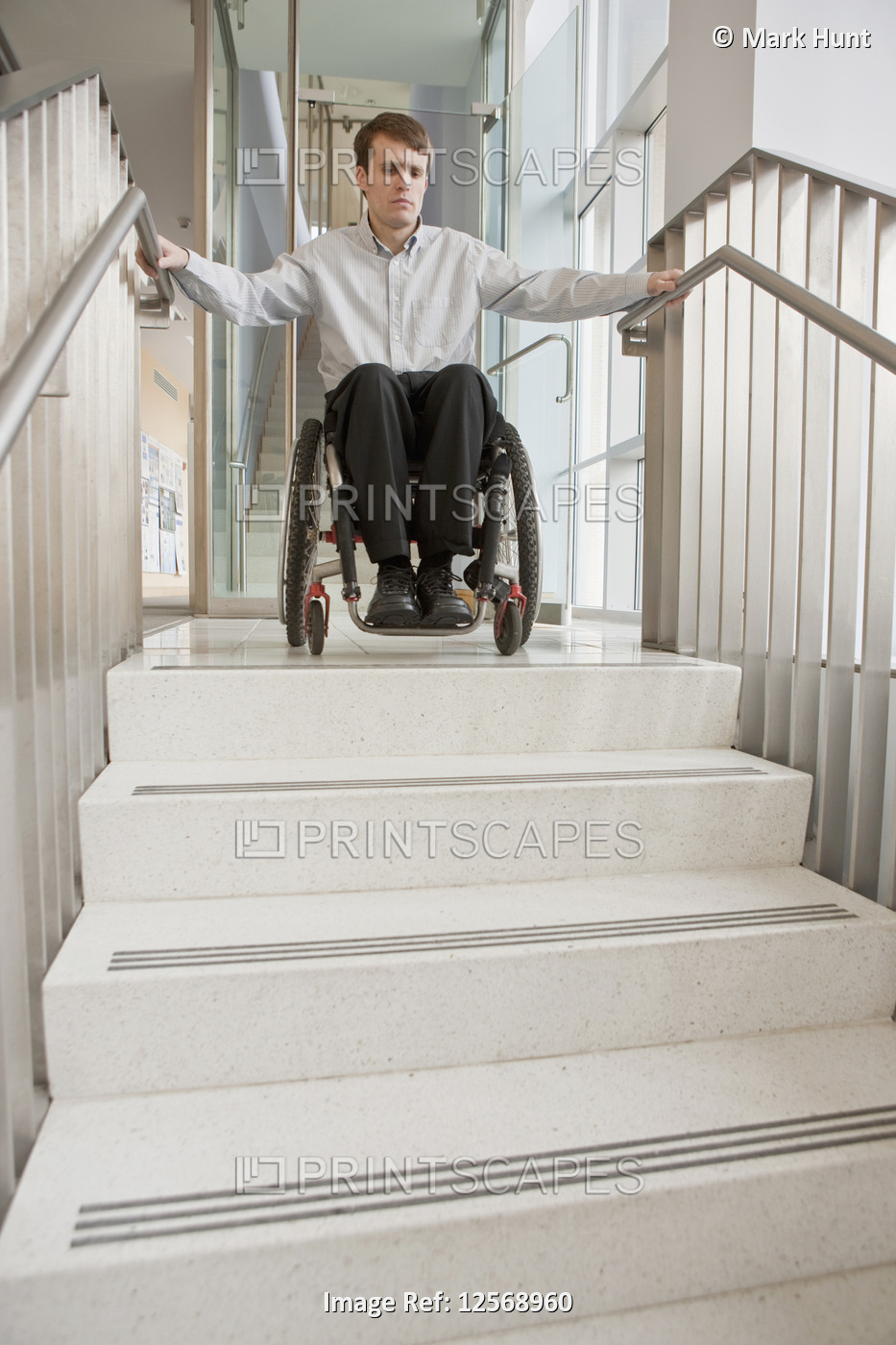 Businessman with spinal cord injury in a wheelchair at the top of stairs