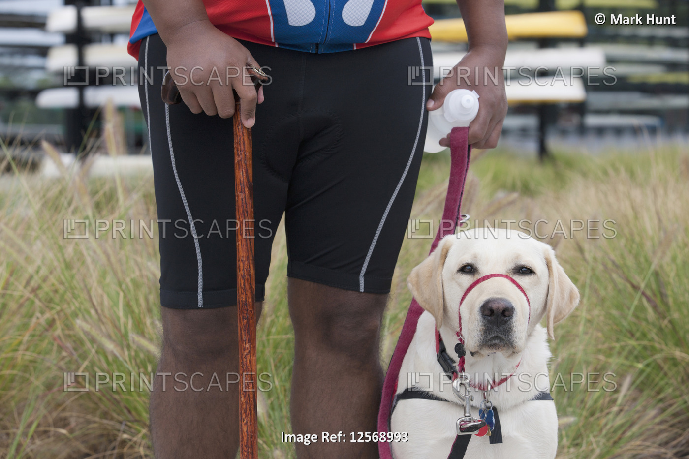 Man with spinal cord injury using a cane and standing with a service dog