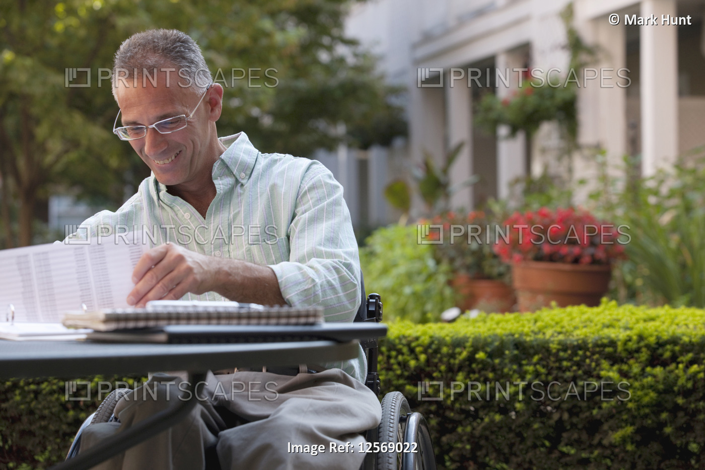 Businessman with spinal cord injury working on documents at a cafÃ©
