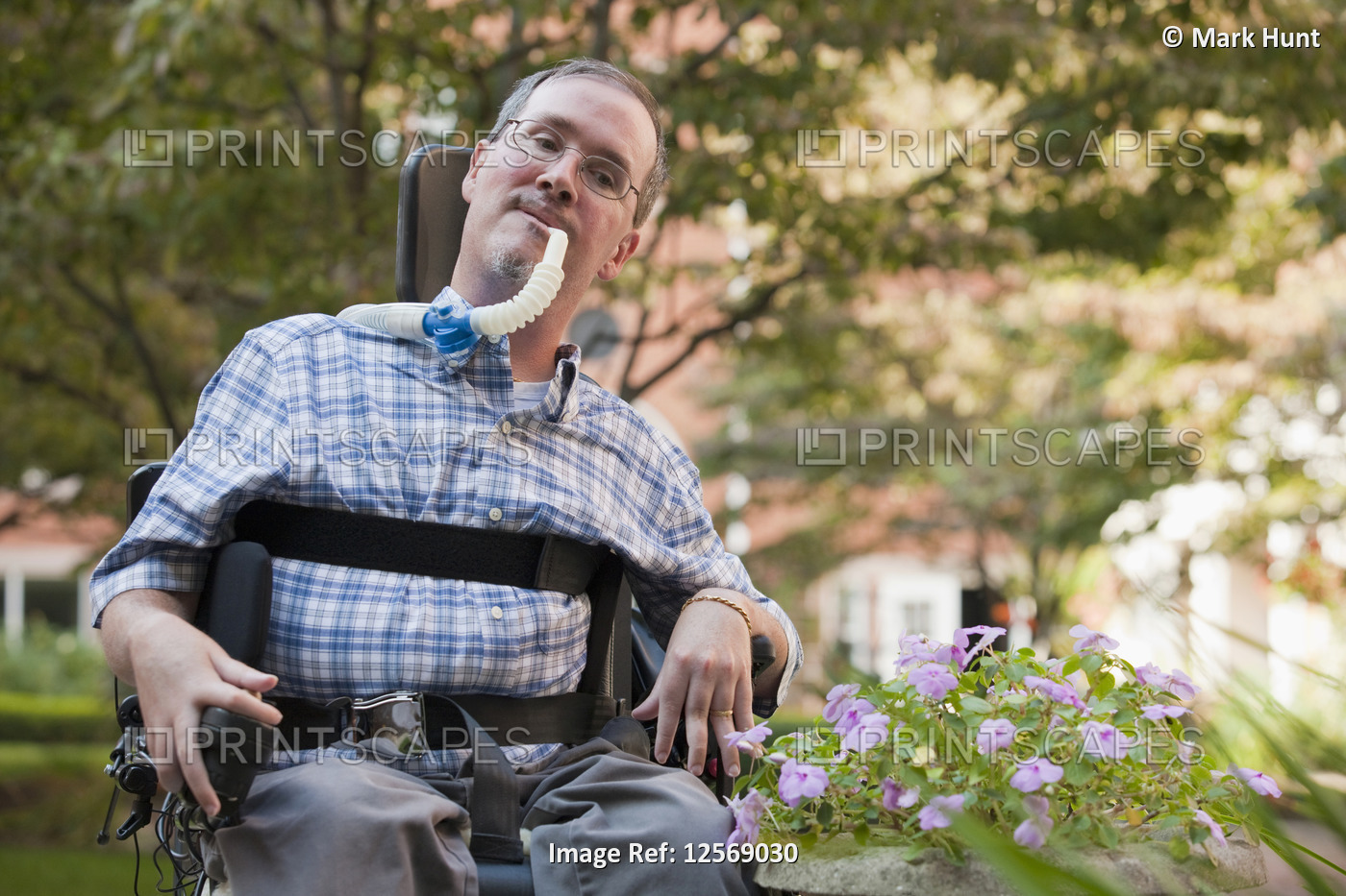 Man with Duchenne muscular dystrophy sitting in a wheelchair with a breathing ...