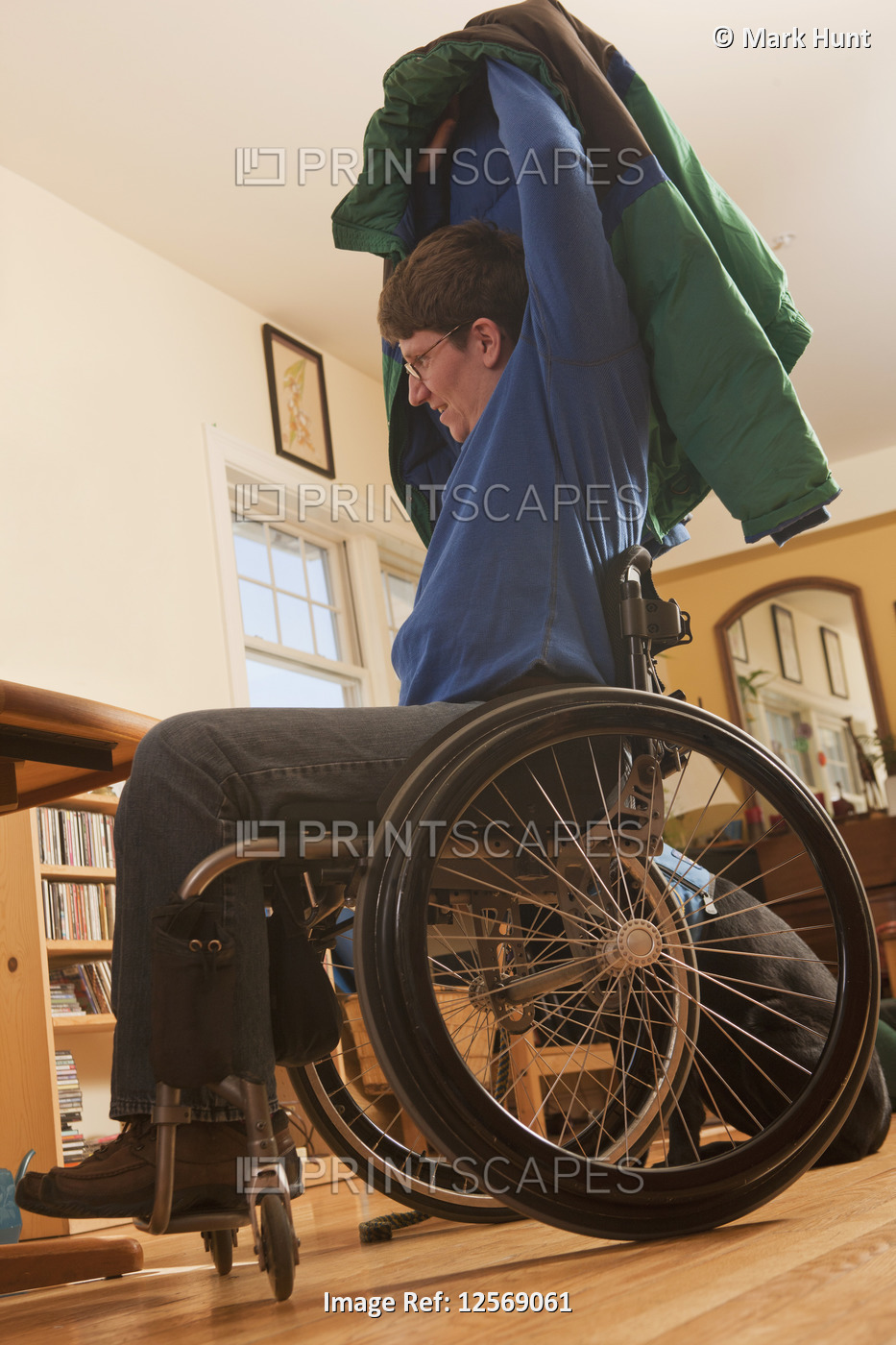 Woman with multiple sclerosis in a wheelchair putting on her coat without help