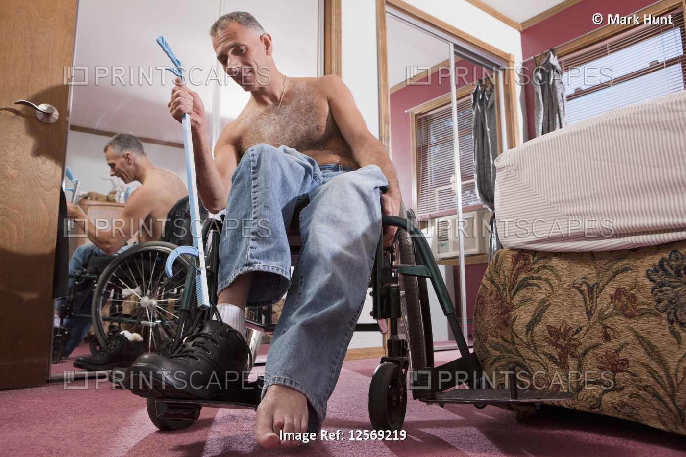 Man with spinal cord injury untying his shoes with an extension tool
