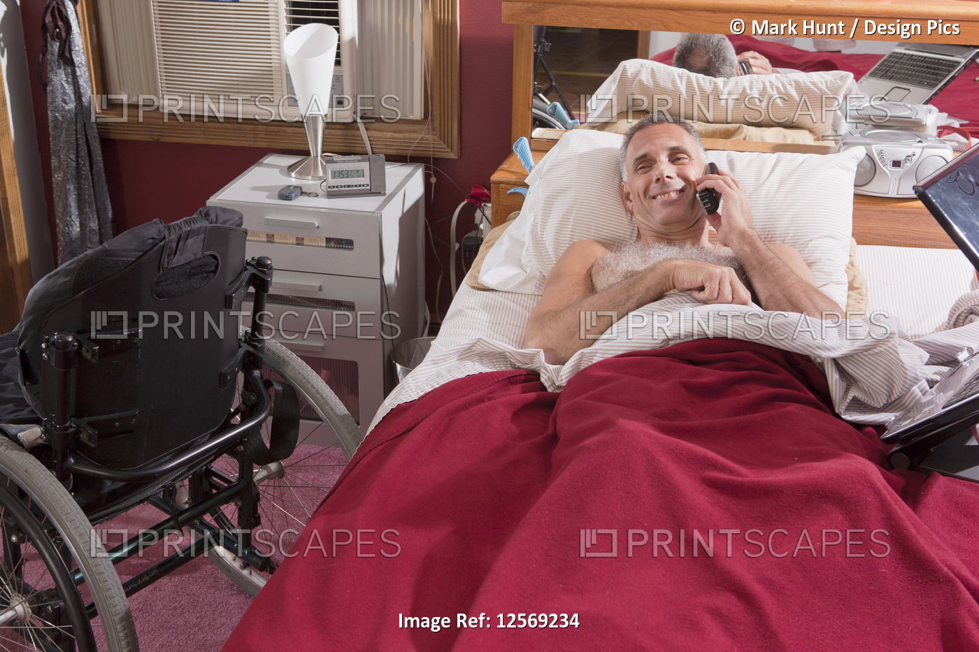 Man with spinal cord injury lying on the bed talking on a mobile phone