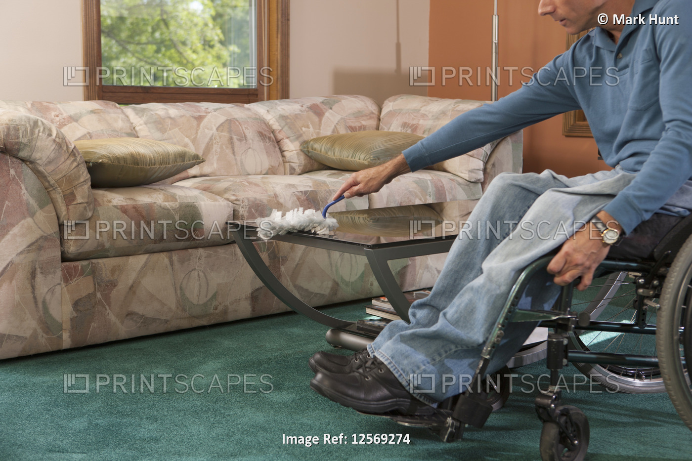 Man with spinal cord injury in a wheelchair dusting furniture
