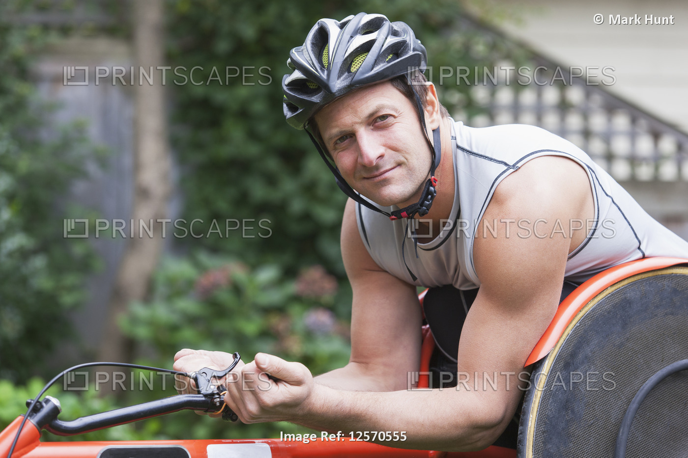 Disabled man with muscular arms sits in cycling equipment and looks at the ...