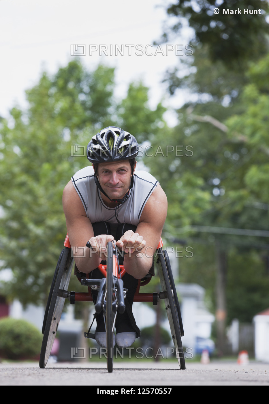 Disabled man with muscular arms sits in cycling equipment and looks at the ...