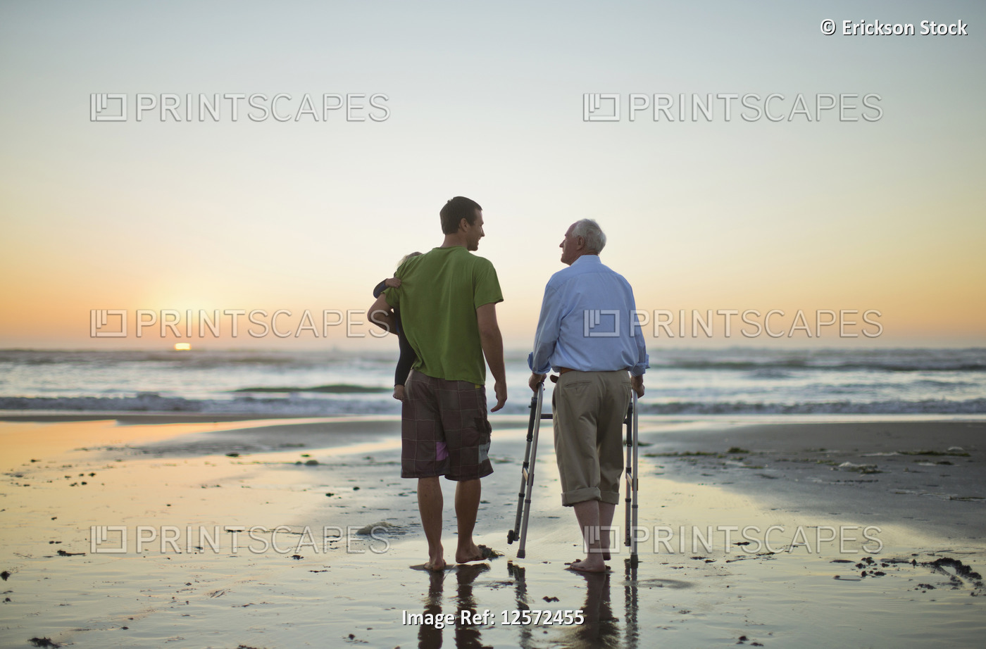 Senior man with a walking aid on the beach with his son and grandchild