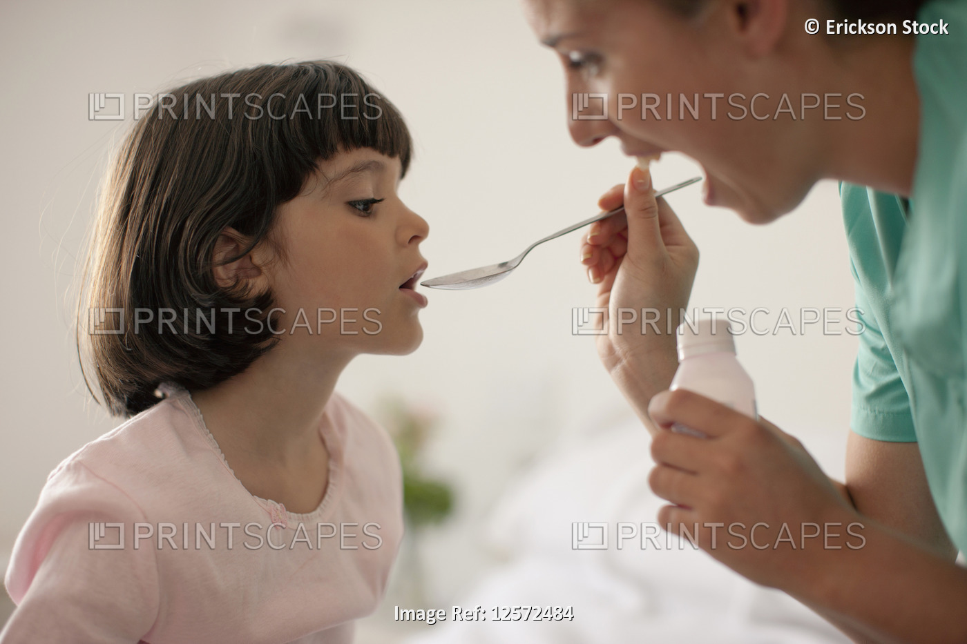 Nurse giving young girl medicine with spoon