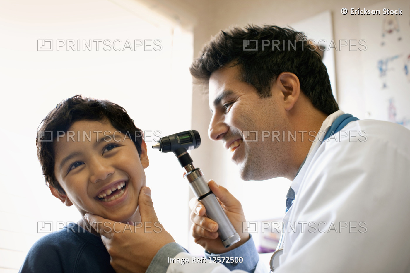 Doctor examining his young patient's ear with otoscope.
