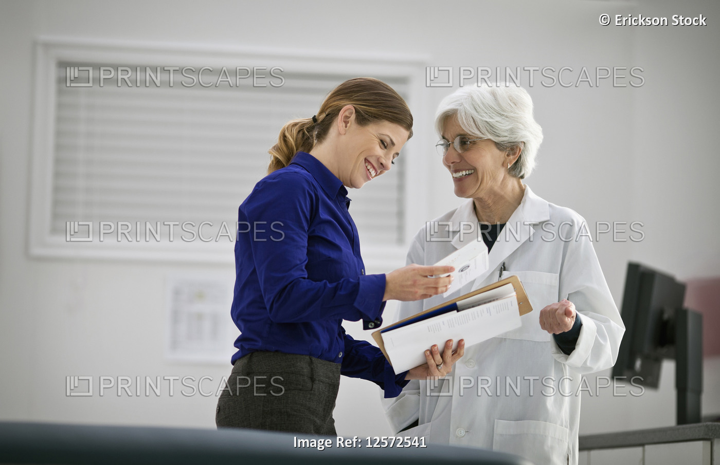 Smiling female doctor speaking with a pharmaceutical representative inside a ...