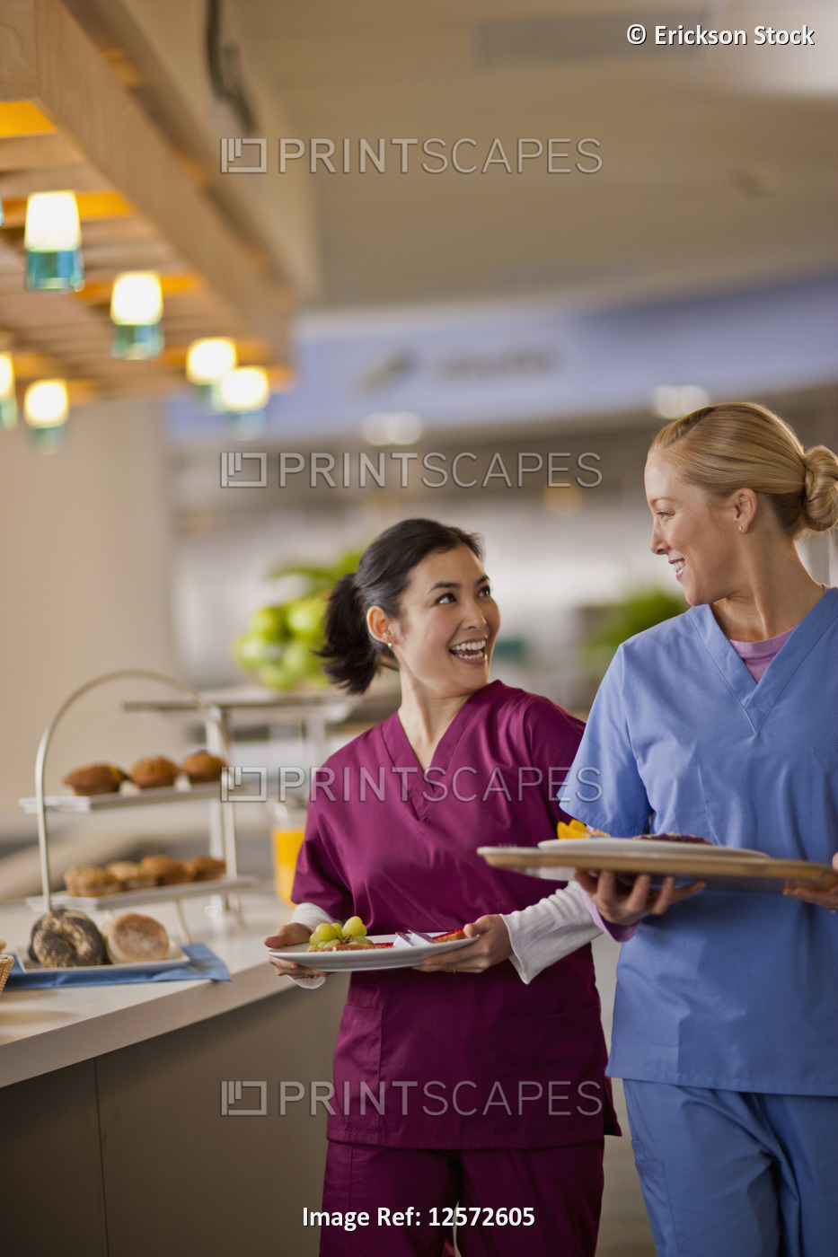 Two young nurses smile and chat together as they get their lunch from the ...
