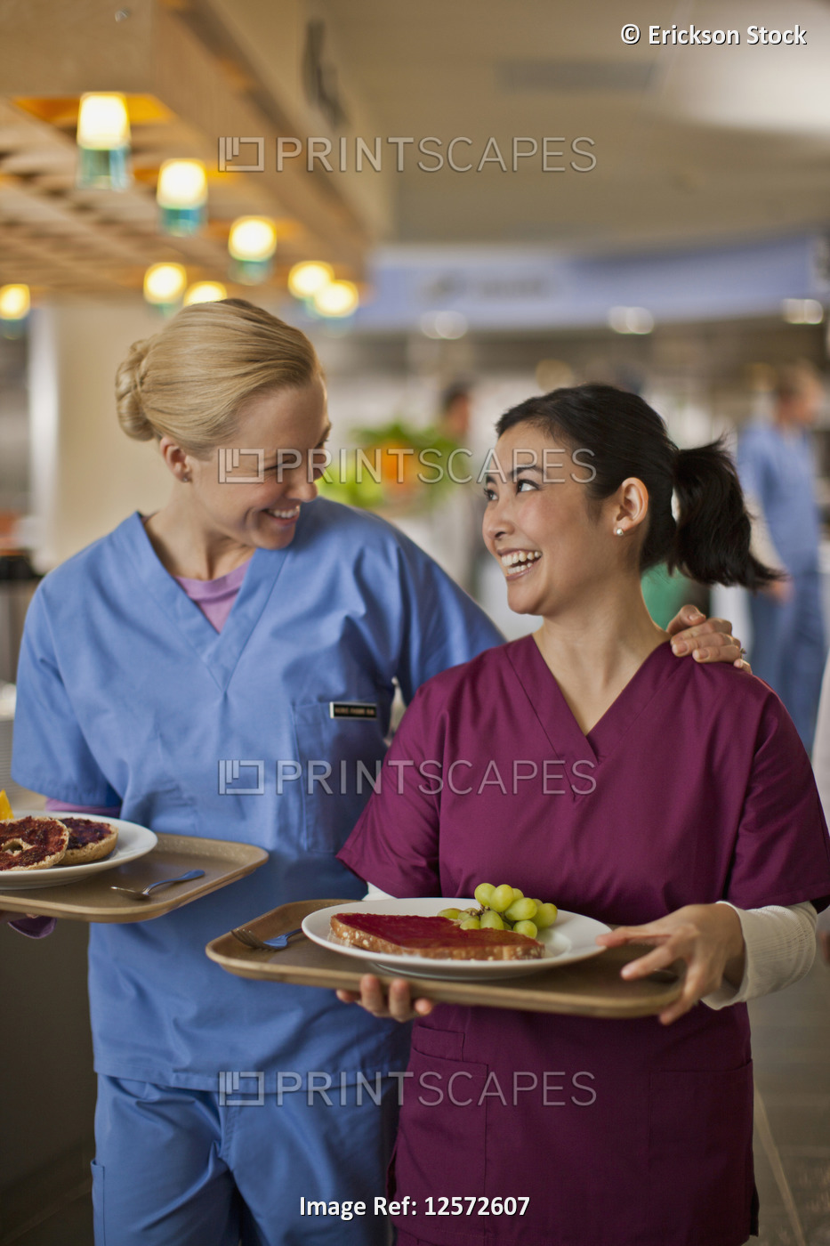 Two young nurses smile and chat together as they get their lunch from the ...