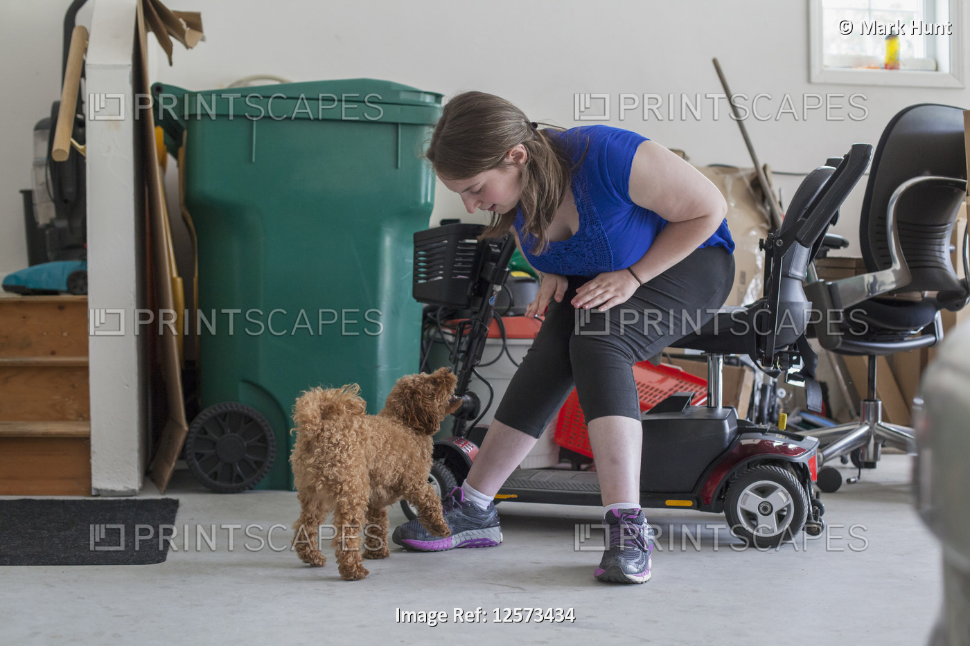 Young Woman with Cerebral Palsy playing with her dog while her scooter is there