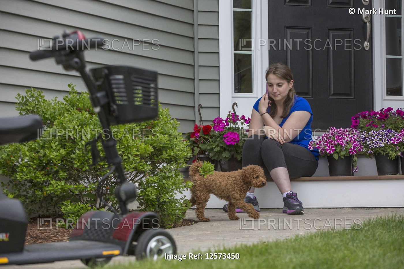 Young Woman with Cerebral Palsy playing with her dog while her scooter is there