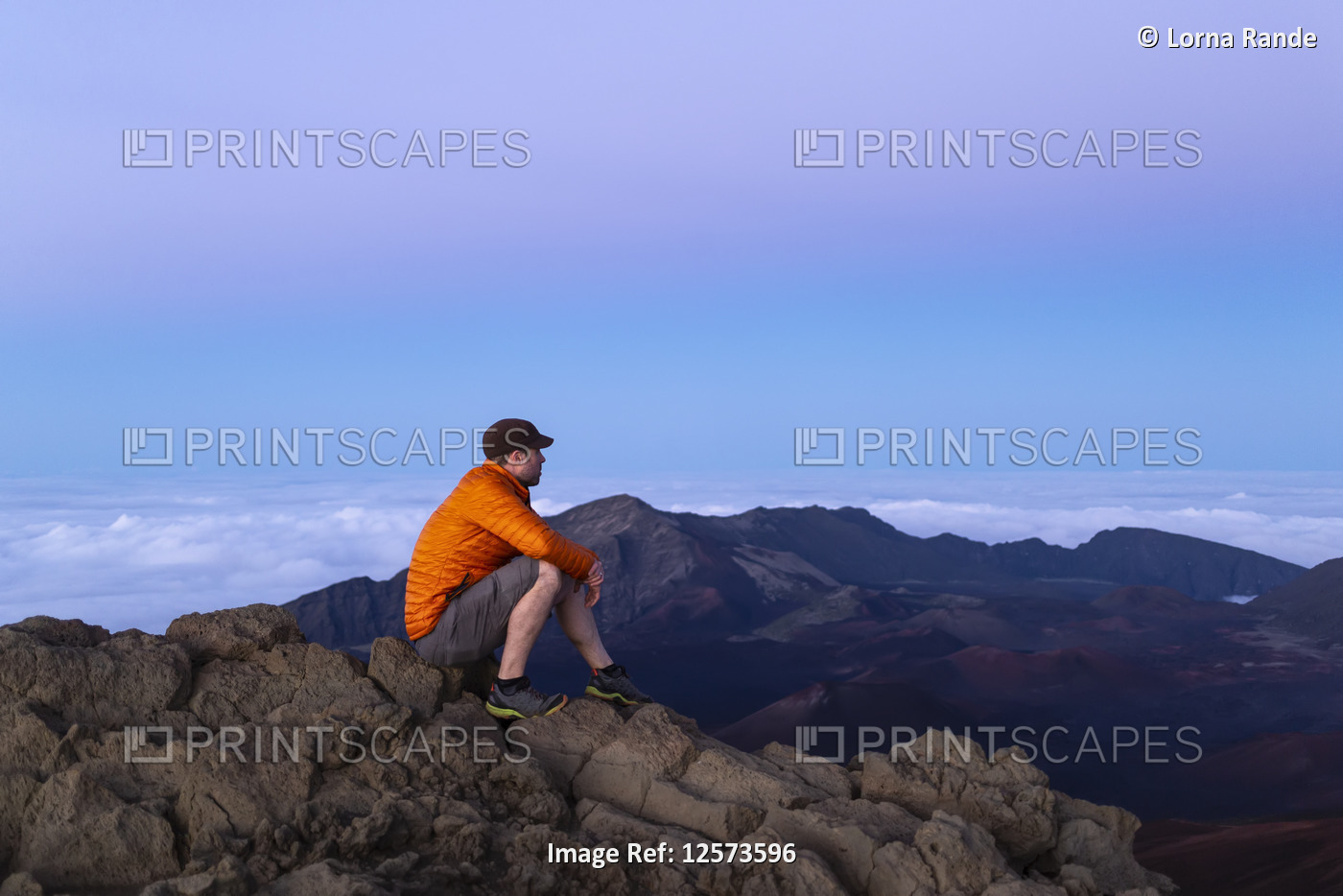 Tourist sits on a mountain summit looking out, Haleakala; Maui, Hawaii, United ...