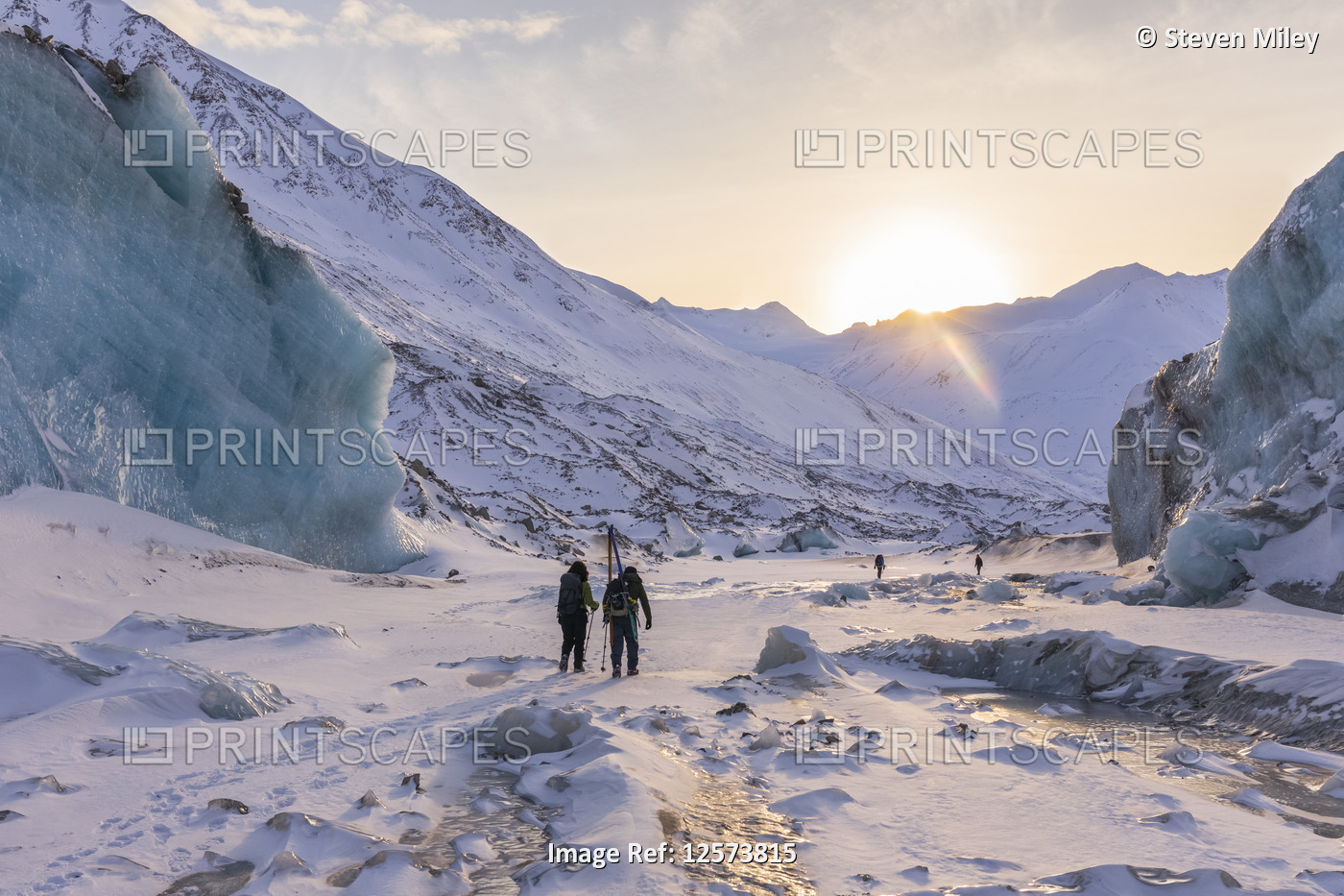 Winter hikers explore Black Rapids Glacier as the sun sets over the Alaska ...