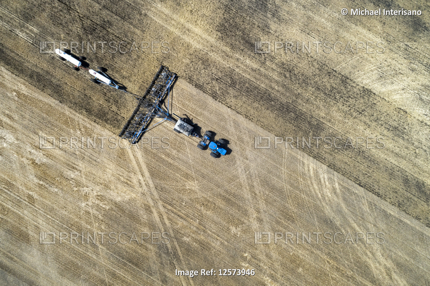 Aerial view of air seeder in field with white ammonia tanks, near Beiseker; ...
