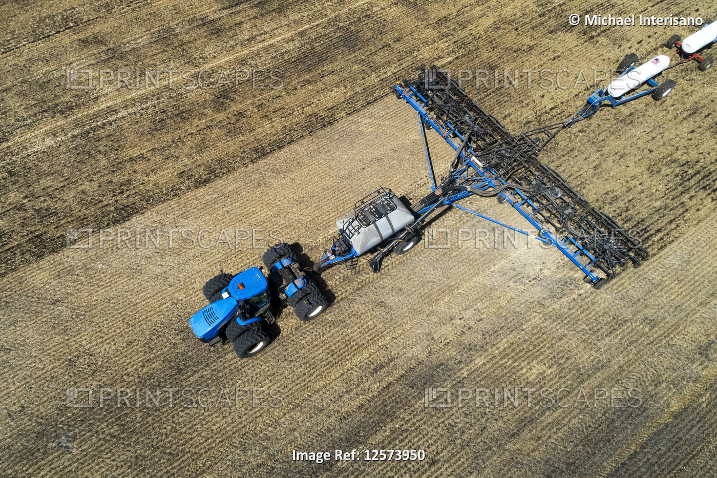 Aerial view of air seeder in field with white ammonia tanks, near Beiseker; ...