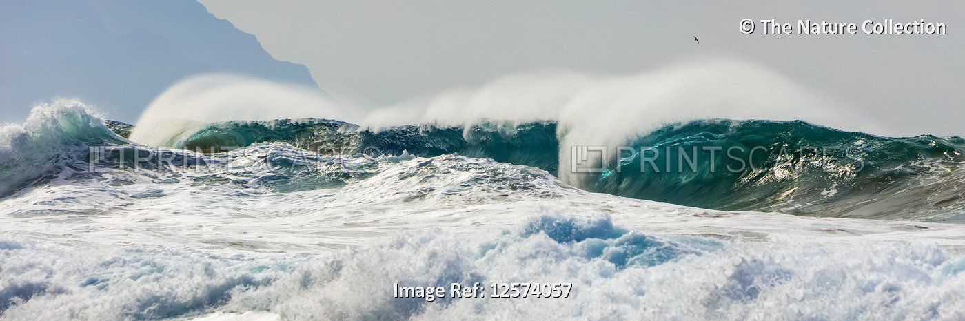 Ocean waves crashing into the shore off the Na Pali coast; Kauai, Hawaii, ...