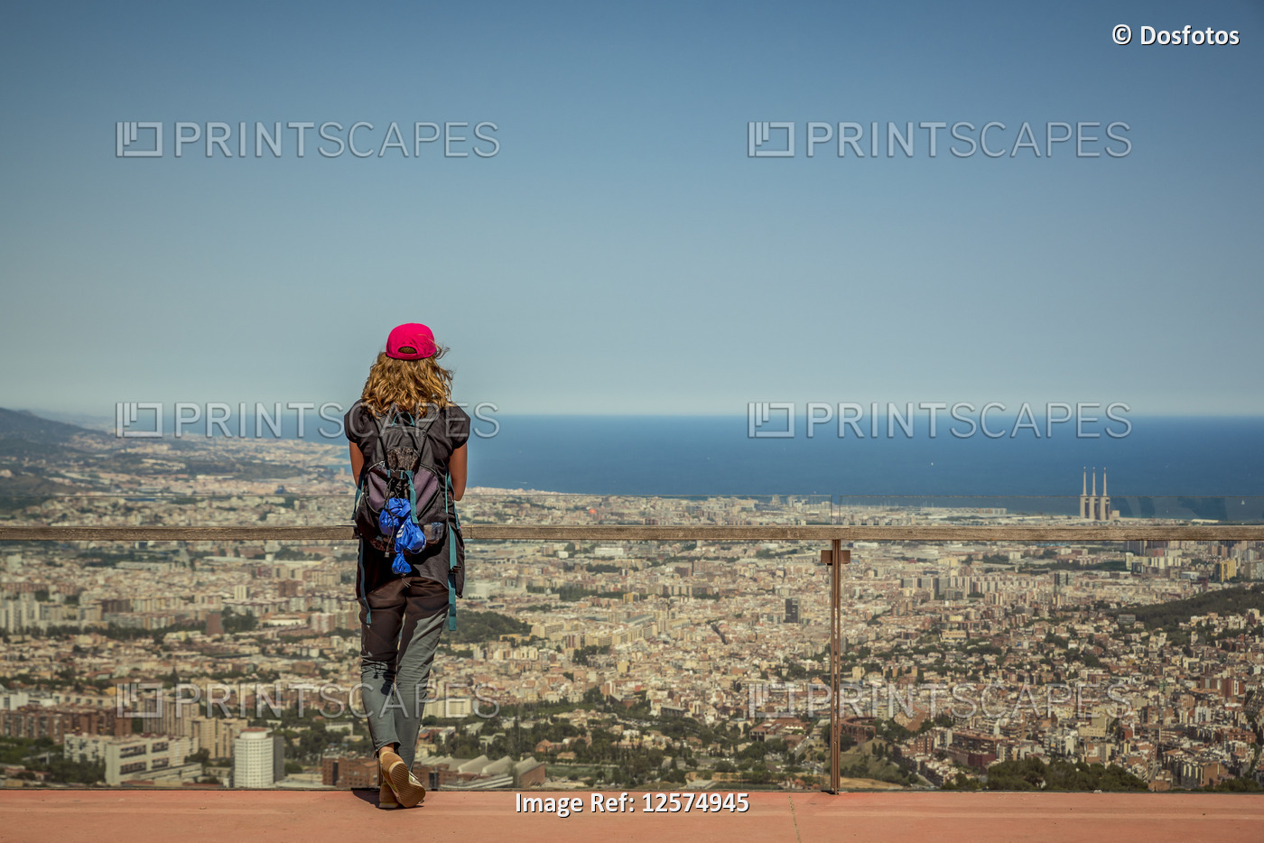 Tourist standing at a railing in Tibidabo Amusement Park overlooking the city ...